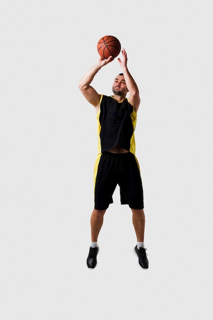 ボールを投げながら空中でポーズのバスケットボール選手の正面図 プレミアム写真
