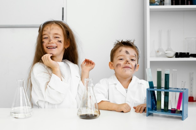 試験管と失敗した実験を伴う実験室の少女と少年の科学者の正面図