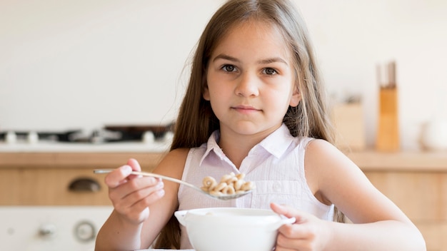 朝食にシリアルを食べる女の子の正面図 無料の写真