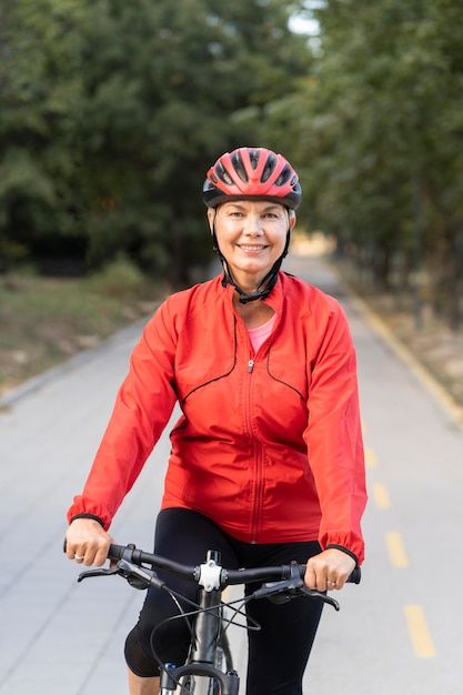 自転車に乗って屋外で笑顔の年配の女性の正面図 無料の写真