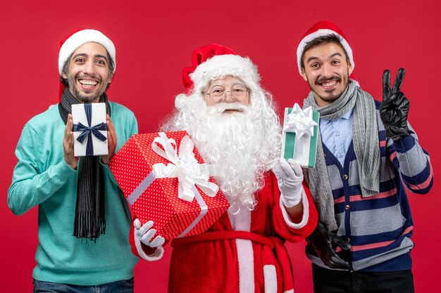 Free Photo | Front view santa claus with two males holding presents on ...