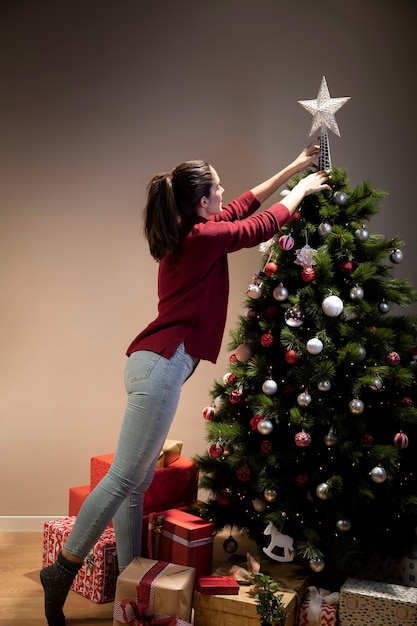 Free Photo Front View Woman Putting On Christmas Tree The Star 1568