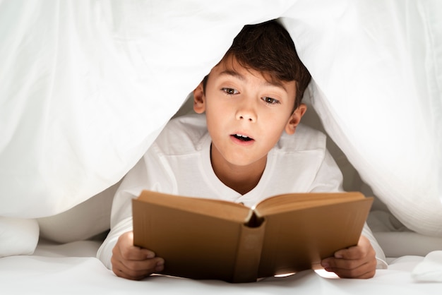 Front view young boy at home reading | Free Photo