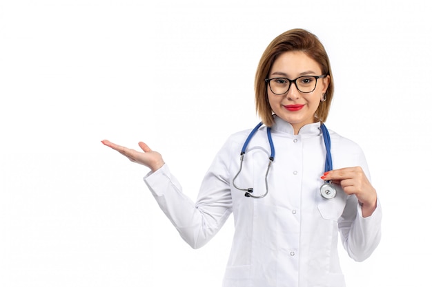 A front view young female doctor in white medical suit with stethoscope smiling on the white Free Photo