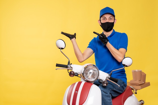 Front view young male courier in blue uniform and mask on yellow background Free Photo