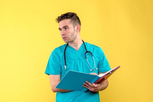 Free Photo | Front view of young male doctor with analyzes on a yellow wall