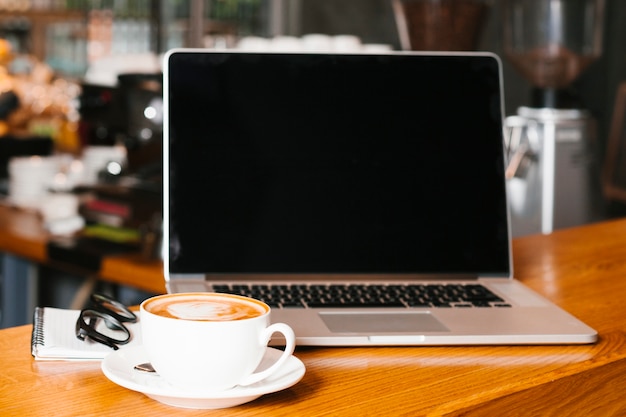 Frontview laptop and coffee on wooden surface | Free Photo