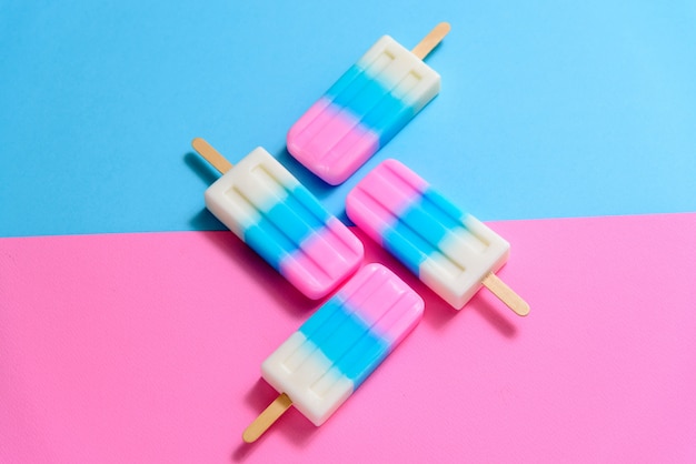 Fruit ice cream stick , popsicle , ice pop or freezer pop with copyspace on blue and pink pastel background or texture Premium Photo