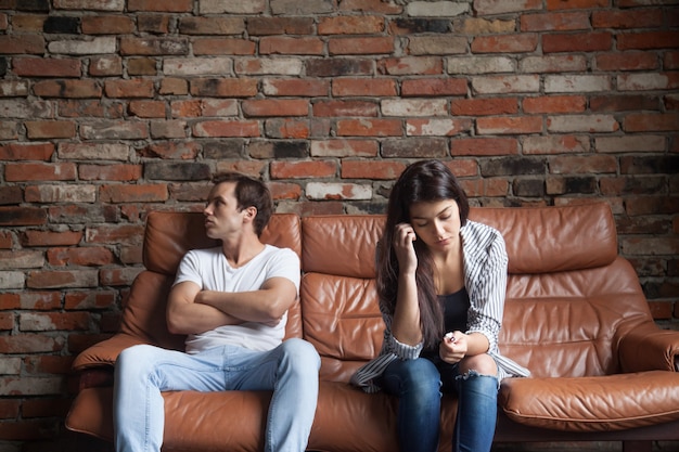 Разочарованный расстроен пара после ссоры, сидя на диване у себя дома | Бесплатно Фото