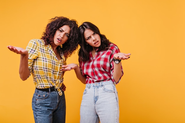 Free Photo Frustrated Women In Jeans Look Inquiringly Spreading Their Arms To Side Portrait Of Girls With Curls