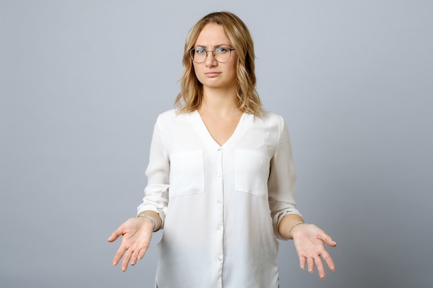 Premium Photo | Frustrated young woman shrugs shoulders with her arms ...