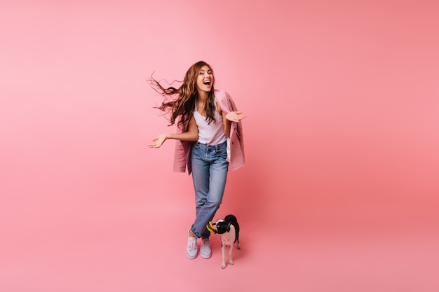 Free Photo Full Length Portrait Of Brunette Lady In Jeans Posing With Dog Indoor Portrait Of Beautiful Female Model Standing Beside French Bulldog