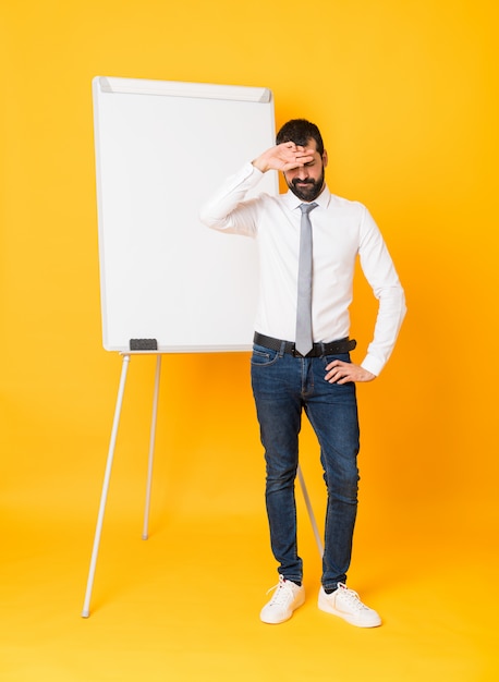 Full-length shot of businessman giving a presentation on white board over isolated yellow background with tired and sick expression Premium Photo