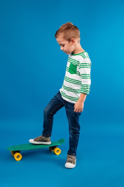 Free Photo | Full length side view of young boy posing with skateboard