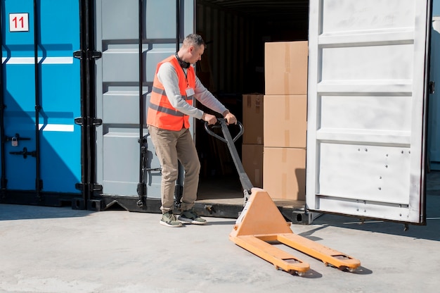 Free Photo | Full shot man carrying pallet truck