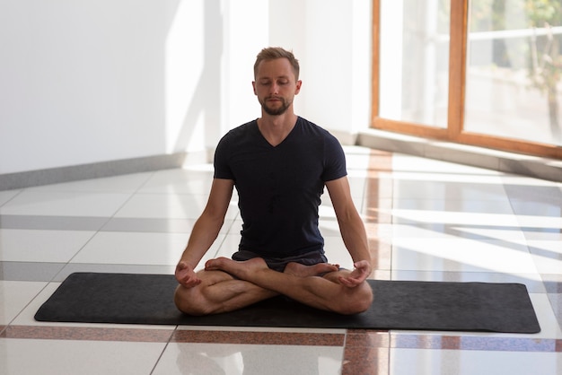 Premium Photo | Full shot man doing sukhasana pose inside on mat