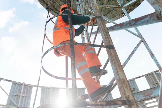 Full shot man with safety equipment on ladder Free Photo