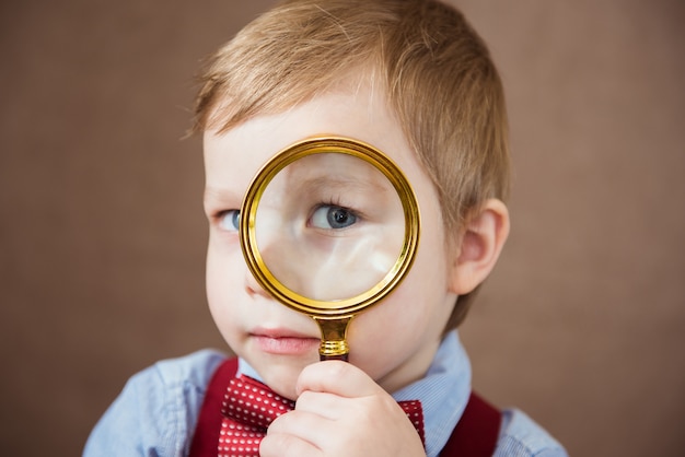 Funny boy looking through magnifying glass with surprise. close up | Premium Photo