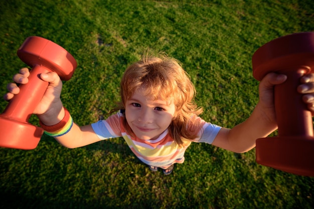 Premium Photo | Funny child exercise with dumbbells on grass outside ...