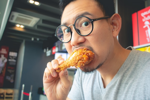 Premium Photo Funny Face Of Man Eat Fried Chicken In The Franchise Cafe