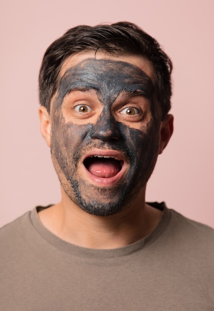 ピンクの彼の顔に化粧マスクを持つ面白い男 プレミアム写真