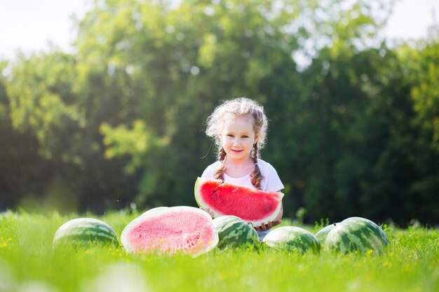 サマーパークの屋外で面白い子供とスイカ 子供 健康食品 プレミアム写真