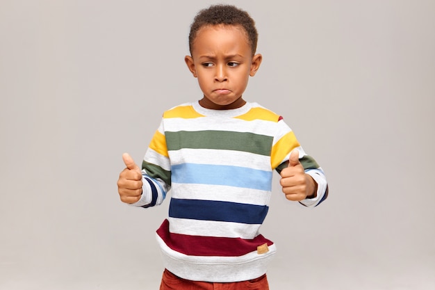 Free Photo Funny Little African American Boy In Striped Pullover Posing Giving Thumbs Up Saying Well Done Praising Someone For Good Excellent Job Success At Study Or Work Black Child Approving