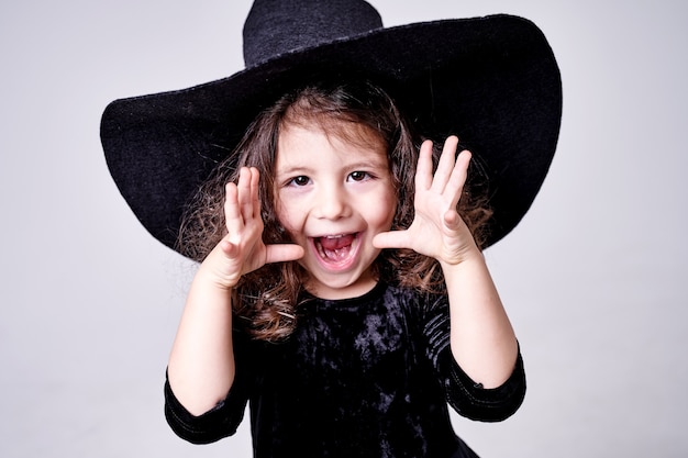 帽子をかぶった面白い魔女の女の子は人々を怖がらせます プレミアム写真