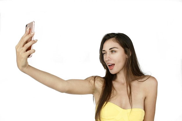 Funny woman takes selfie on her phone standing on white background Free Photo