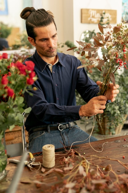 無料の写真 花の花束を持って長い髪を持つ庭師男