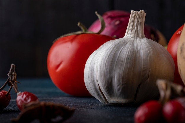 Free Photo | Garlic gloves and tomatoes on black table.