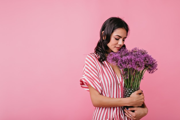 ロマンチックな気分の優しい若い女性は 花の腕一杯を見てかわいいです スタイリッシュな服装のヨーロッパの女性の肖像画 無料の写真