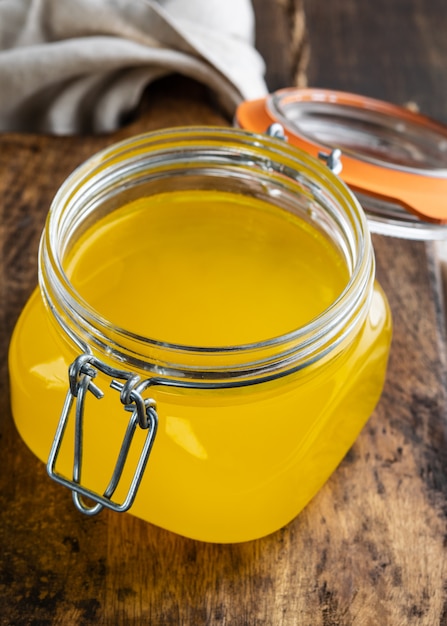 Premium Photo | Ghee or melted butter in a jar on wooden table.