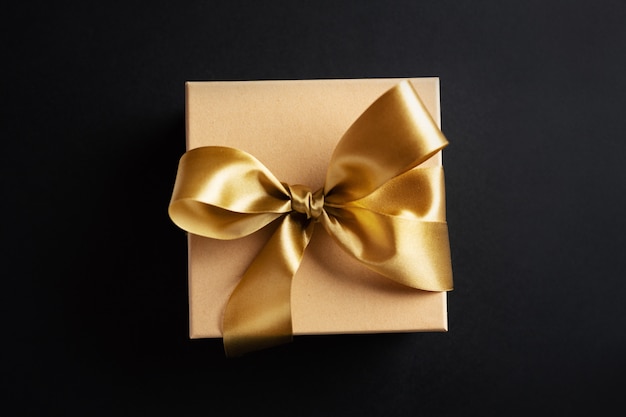 Gift box with golden ribbon on dark surface Free Photo