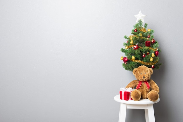 Gift Boxes Teddy Bear And Small Decorated Christmas Tree On Stool