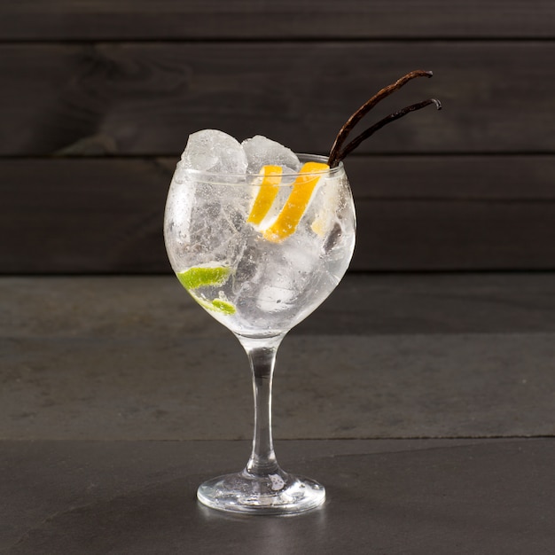 Gin tonic cocktail with ice vanilla lima and lemon on black Premium Photo