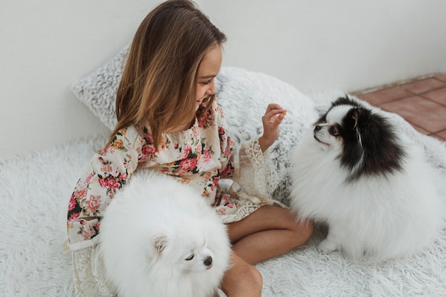 ベッドに座っている女の子とかわいい白い子犬 無料の写真