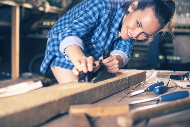 Premium Photo | Girl carpenter working with planer in home workshop ...