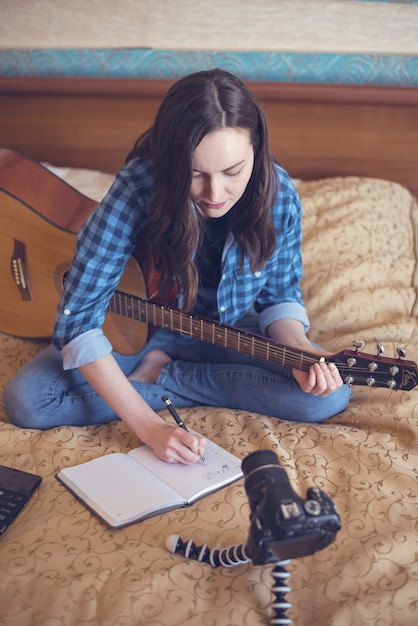 Girl composer writes in notebook composing music on guitar ...