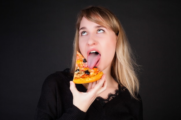 Premium Photo | The girl eats a slice of pizza and makes a face, on a ...