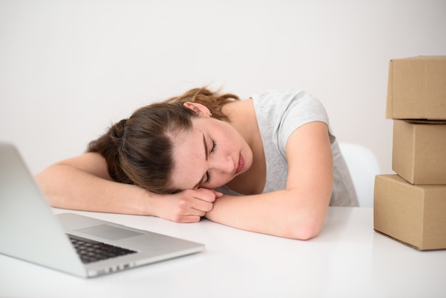 Premium Photo The Girl Fell Asleep At A Table Opposite A Laptop And Boxes Tired After Work Non Stop Work