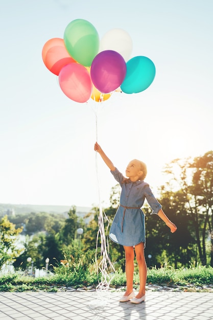 Free Photo Girl holding colorful balloons stretching to the sky and 