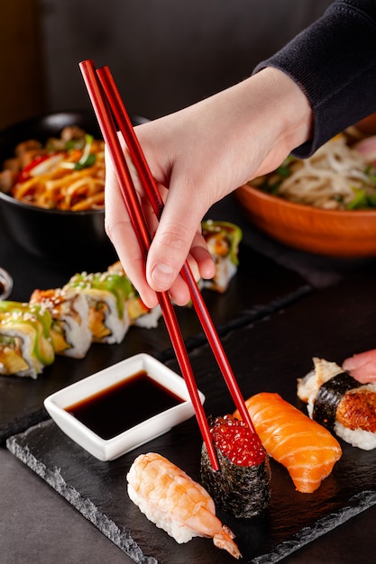 Premium Photo A Girl Holds A Red Chinese Chopsticks And Eat Sushi In A Restaurant