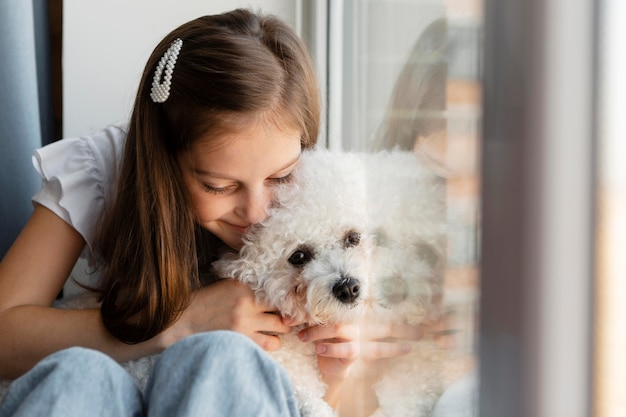 窓際で犬を抱きしめる少女 無料の写真