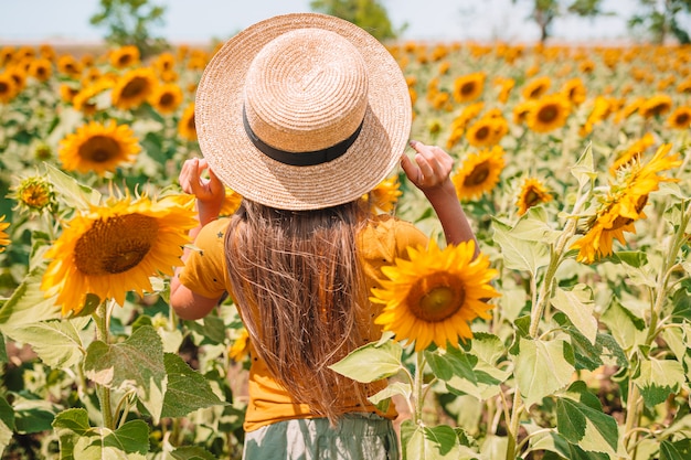 ひまわり畑に麦わら帽子立っている女の子 プレミアム写真