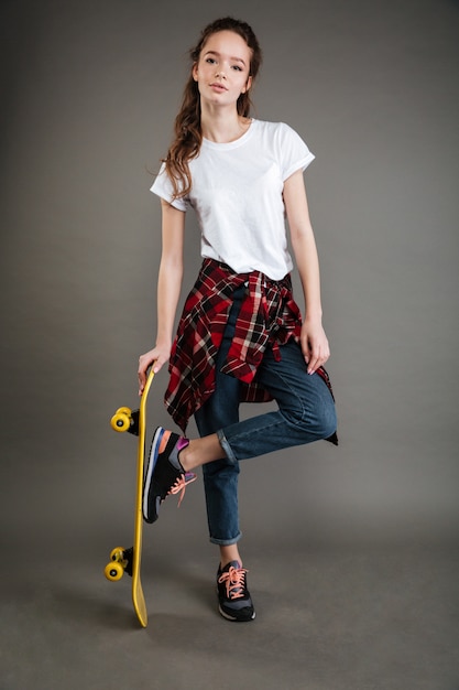 無料の写真 立っているとスケートボードを保持しているカジュアルな服装の女の子