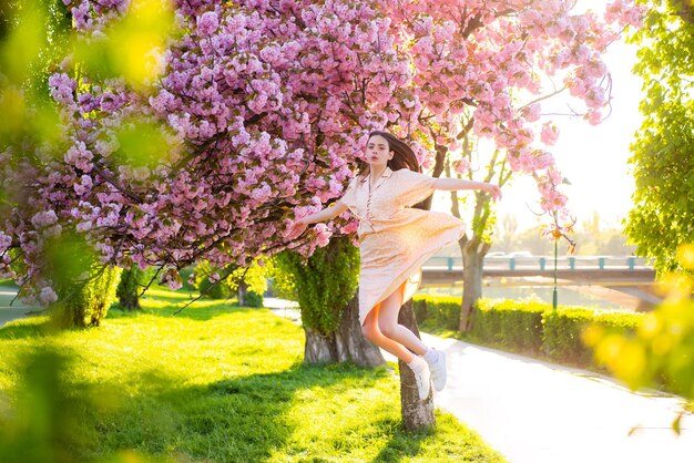 Premium Photo | Girl jumping in pink cherry blossom park holiday with ...