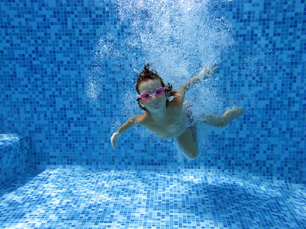 女の子がジャンプして水中プールで泳ぐ プレミアム写真