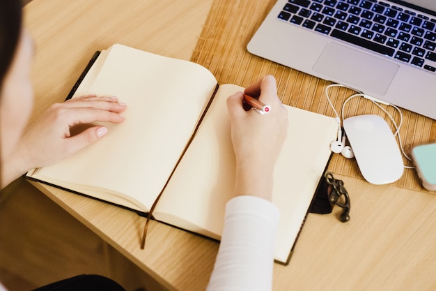 The girl keeps records in her diary, doing business and business, using a computer and a notebook Premium Photo