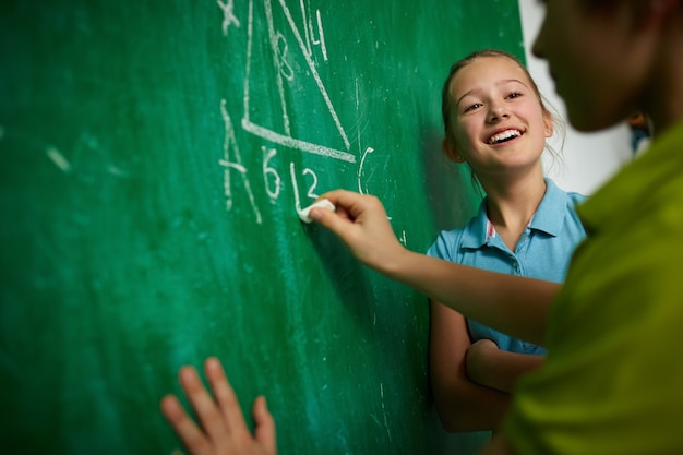 Girl laughing with her colleague writing on the blackboard Photo | Free ...